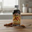 Bottle of Benjamins Cinnamon Extract on a wooden surface with cinnamon sticks and a spoonful of extract.