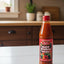 Two bottles of Cal's Hot Pepper Sauce on a store shelf with a price tag.