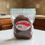 A clear plastic bag of Louis Fruit Preserves Spicy Red Mango dried fruit, showing the reddish-brown slices inside with a prominent red and white label.