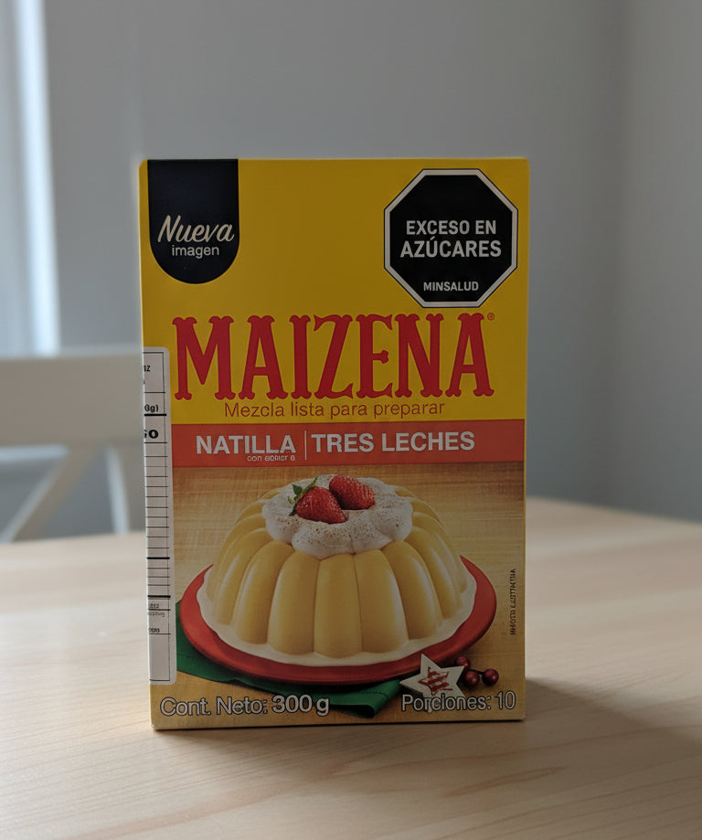 Maizena tres leches pudding mix packaging with a dessert illustration on a wooden surface.