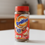 Ovaltine chocolate drink mix container with a red lid on a shelf.