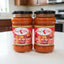 Two jars of Perón Clón hot pepper sauce on a store shelf with a price tag.