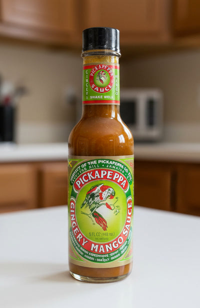 Bottle of Pickapeppa Ginger & Mango Sauce on a store counter.