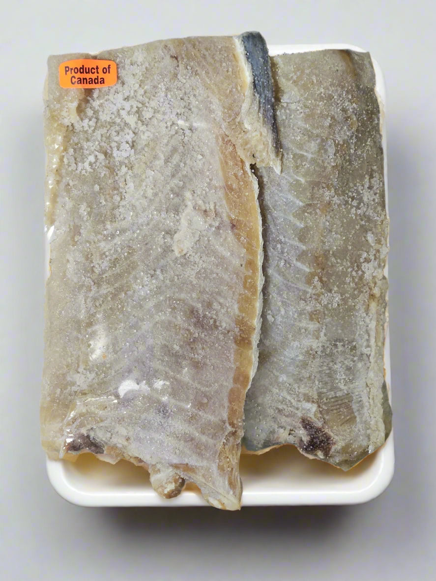 Two salted pollock fillets on a white plate, with a label indicating 'Product of Canada'.