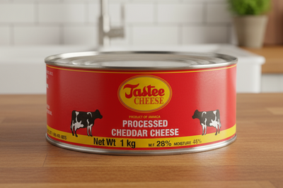 A can of Tastee Cheese, with a red background and an image of a cow. The can indicates a net weight of 1 kg and highlights that it is a product of America.